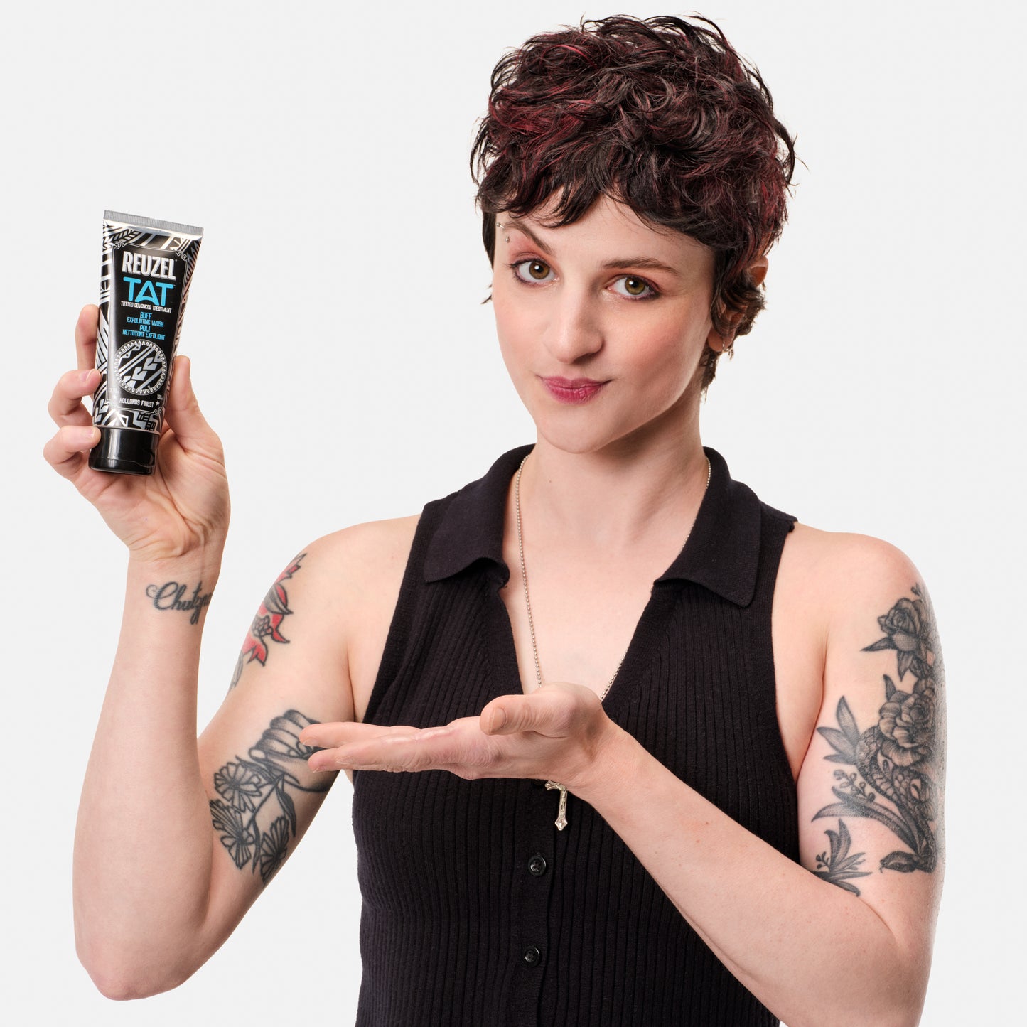 Reuzel TAT Buff Exfoliating Wash for tattoo aftercare, shown in a clear bottle with label, ideal for skin exfoliation and healing.