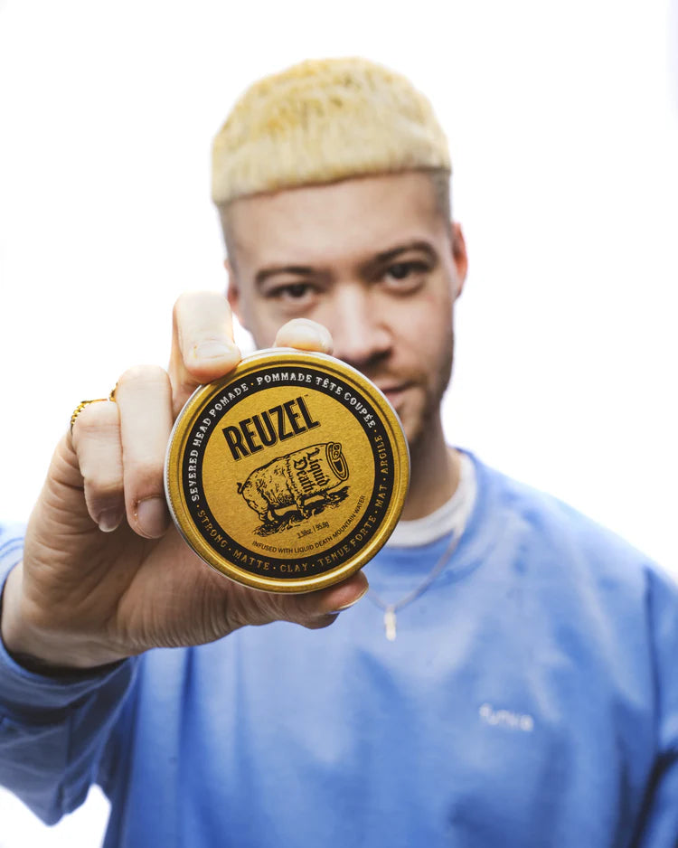 Person holding a Reuzel pomade container against a white background