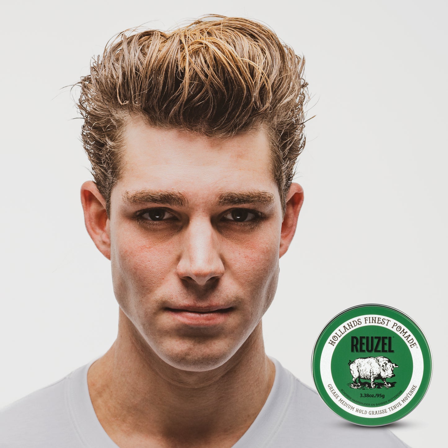 Green Reuzel Pomade grease jar with label showing thick, green pomade for styling hair, placed on a neutral background.