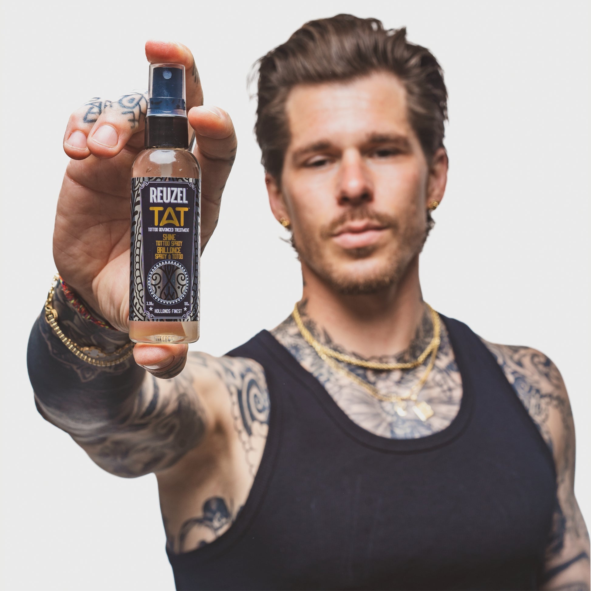 Reuzel TAT Shine Tattoo Spray for aftercare, featuring a sleek spray bottle with label, used to enhance and protect fresh tattoos.