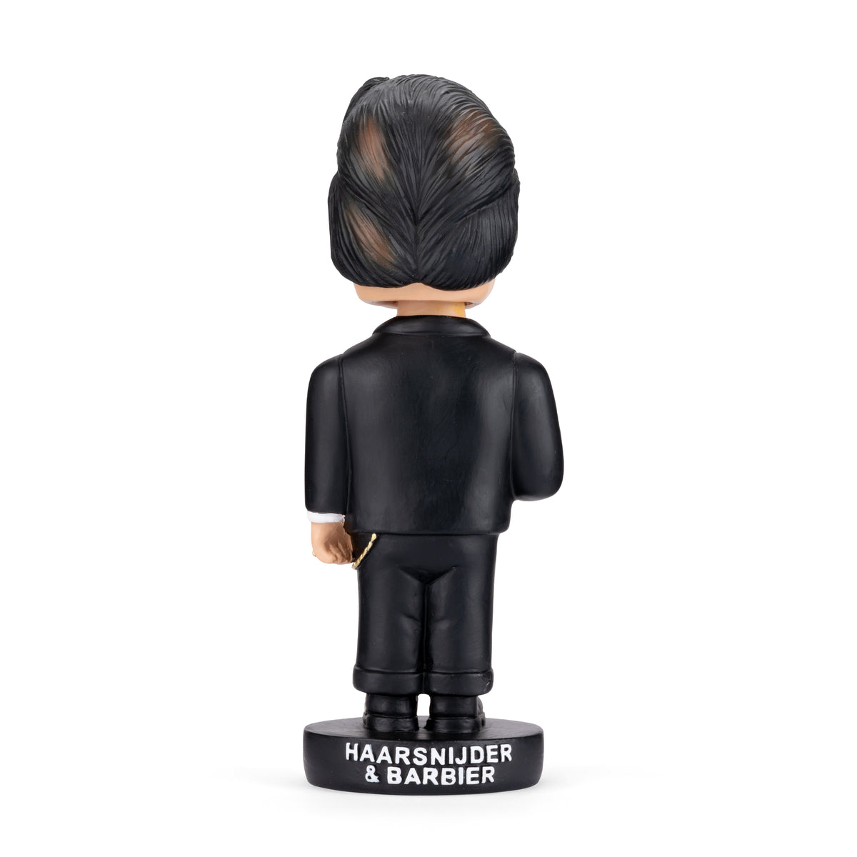 A bobblehead figurine shown from the back, wearing a black suit and standing on a black base labeled 'HAARSNIJDIER & BARBIER'. The figure has dark hair with lighter streaks and a small gold chain detail.