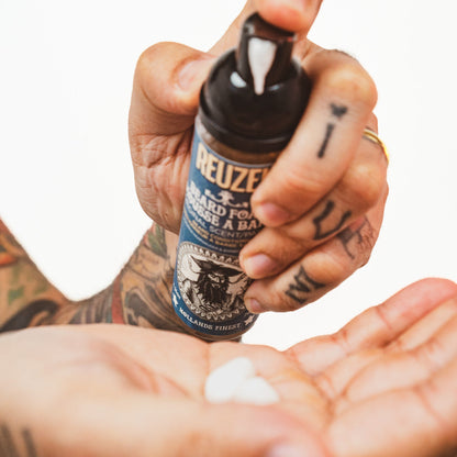 Reuzel Wood & Spice Beard Foam in a bottle, designed for beard grooming and styling with a natural wood and spice scent.