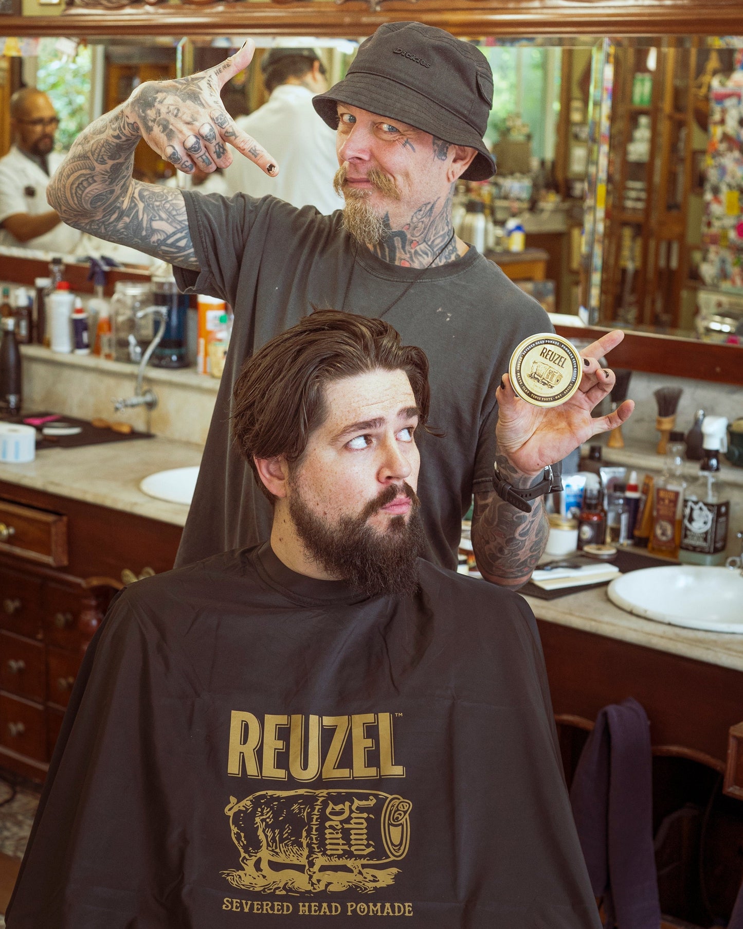 Reuzel X Liquid Death Severed Head barber cape featuring graphic print, designed for professional grooming and barber use.